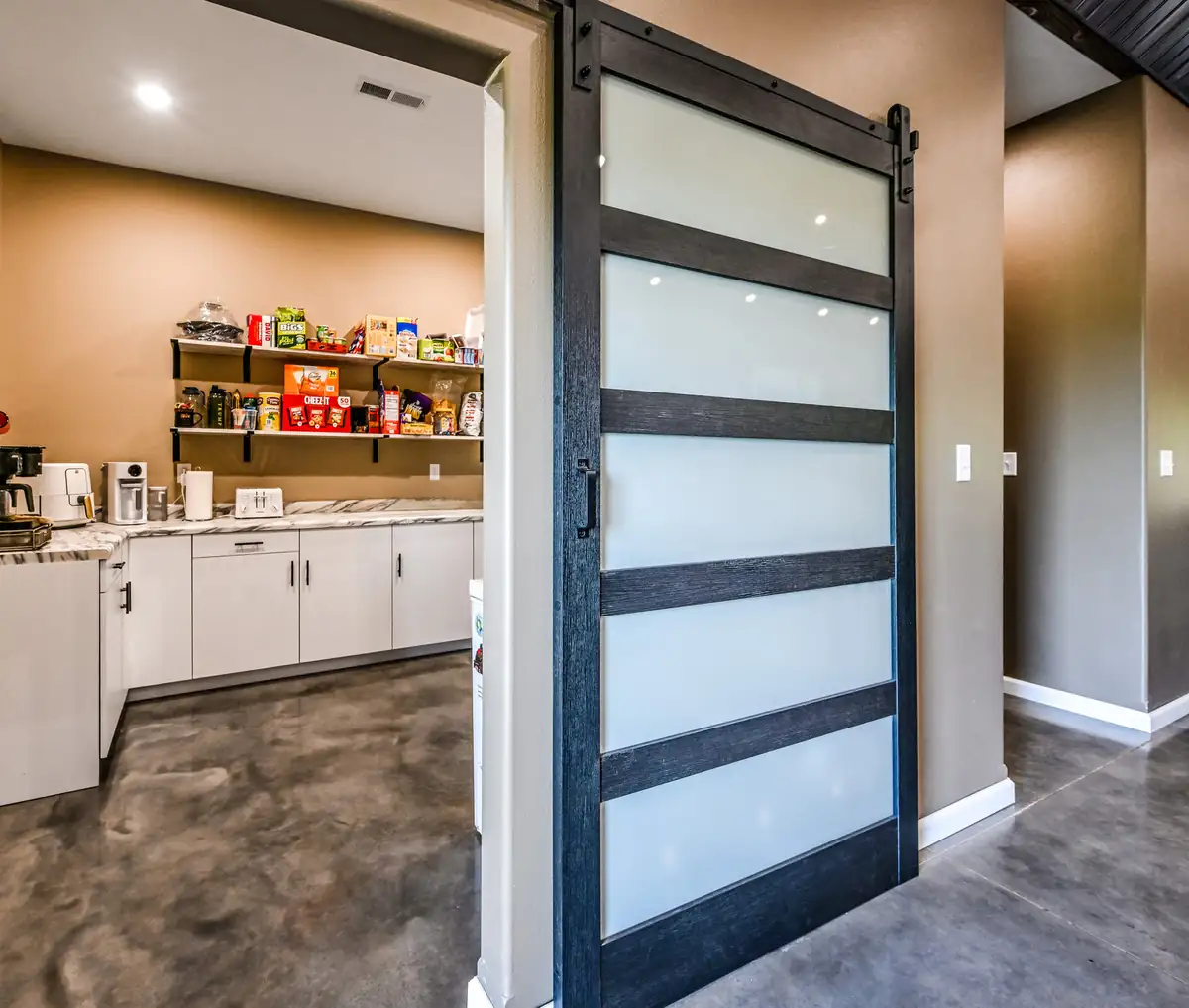 Barndominium interior with a frosted glass sliding barn door into the pantry