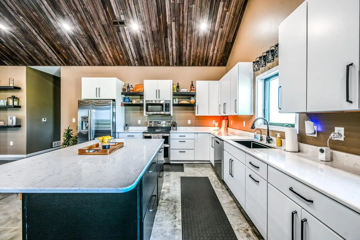 Barndominium kitchen with white cabinets, quartz counters and a wood plank ceiling