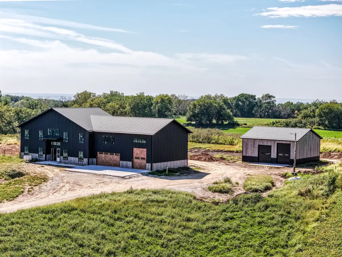 Drone view of a black barndominium with a matching detached shop on open land