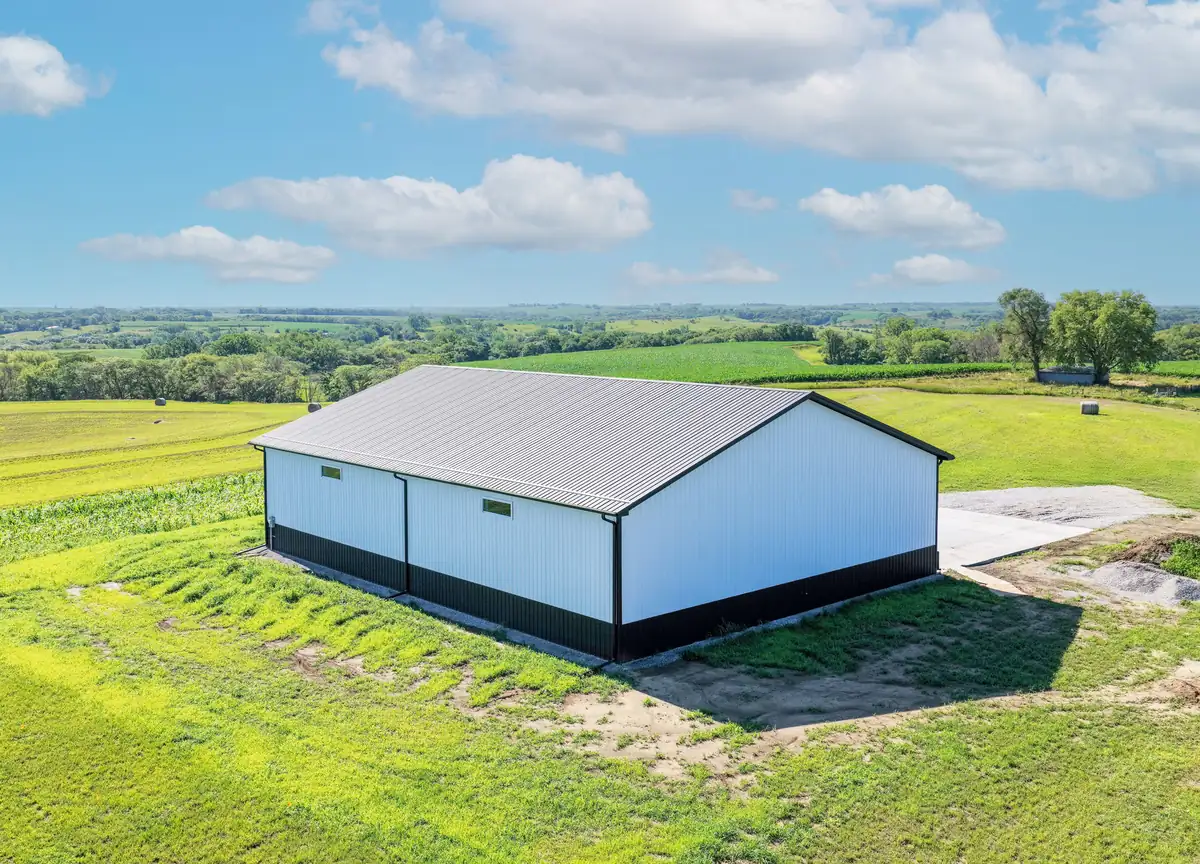 Drone view of a white post frame building on a green hilltop