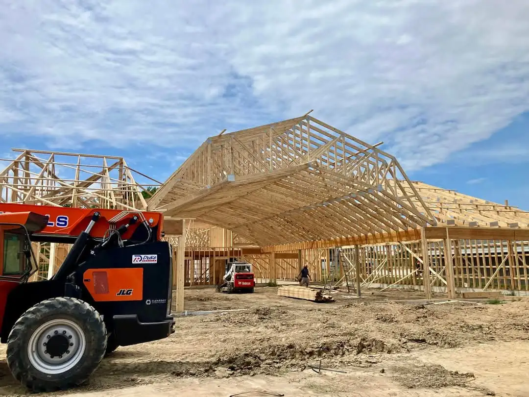 Crew setting trusses with a telehandler on a new building