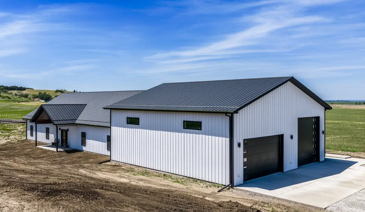 White barndominium with a black-roofed attached two-door garage